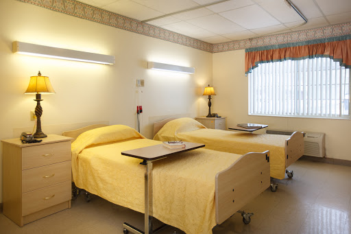 A view of a hospital patient room featuring two beds with yellow bedding, designed for comfort and functionality.