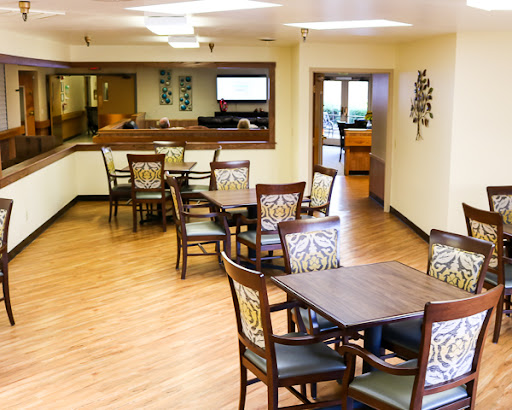 A spacious and inviting dining area featuring wooden tables and chairs, designed for comfort and social interaction.
