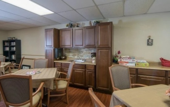 A cozy kitchen area featuring wooden cabinets, tables, and chairs.