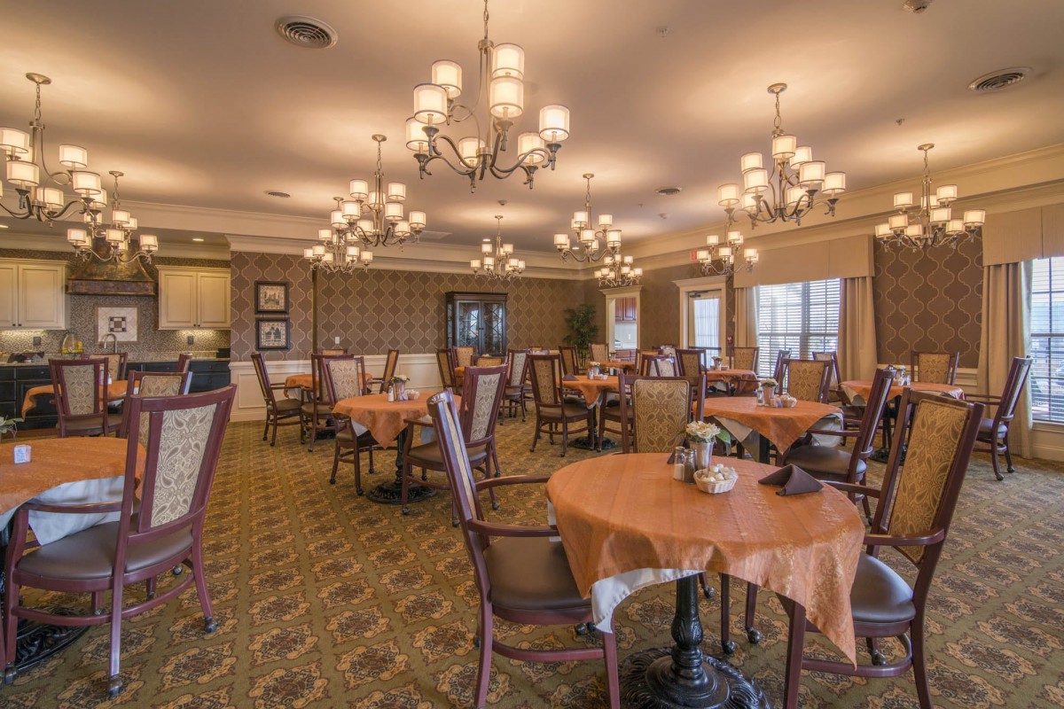 An elegant dining room with tables, chairs, and chandeliers.