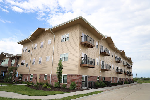 A multi-unit apartment building with balconies and landscaped grounds under a cloudy sky.