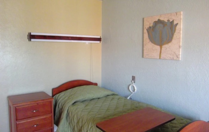 A minimalist hospital room with a single bed and simple decor.