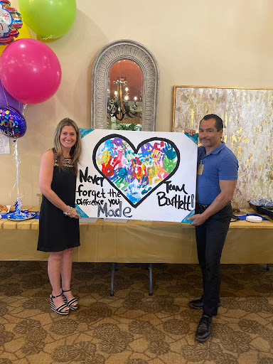 A joyful moment captured as a couple showcases their colorful artwork at a celebration.