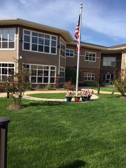 A well-maintained lawn in front of a modern building with an American flagpole.