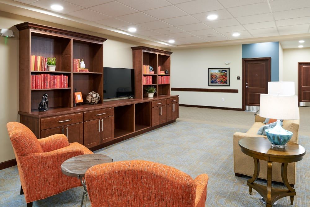 A cozy living room with wooden shelves, a television, and comfortable seating.