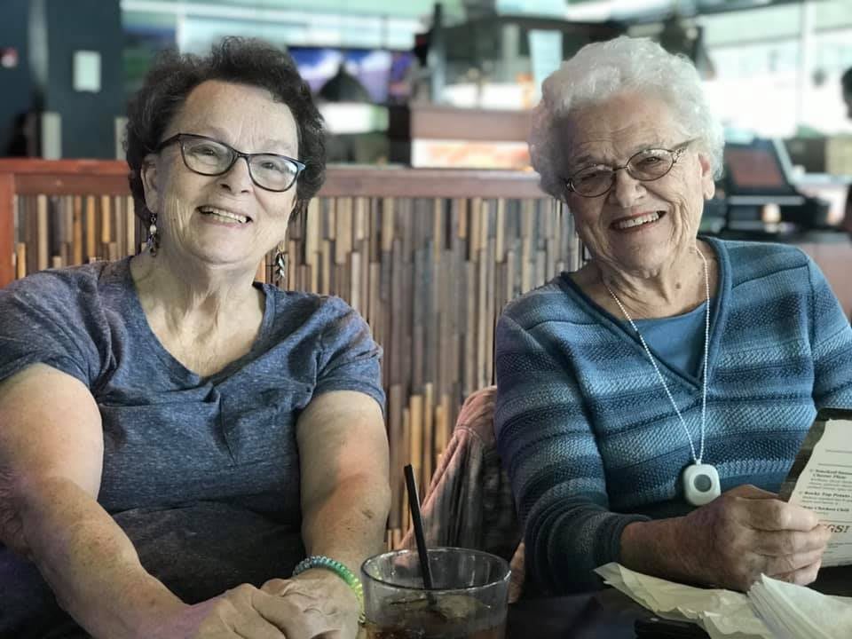 Two elderly women smiling and enjoying time together at a restaurant.