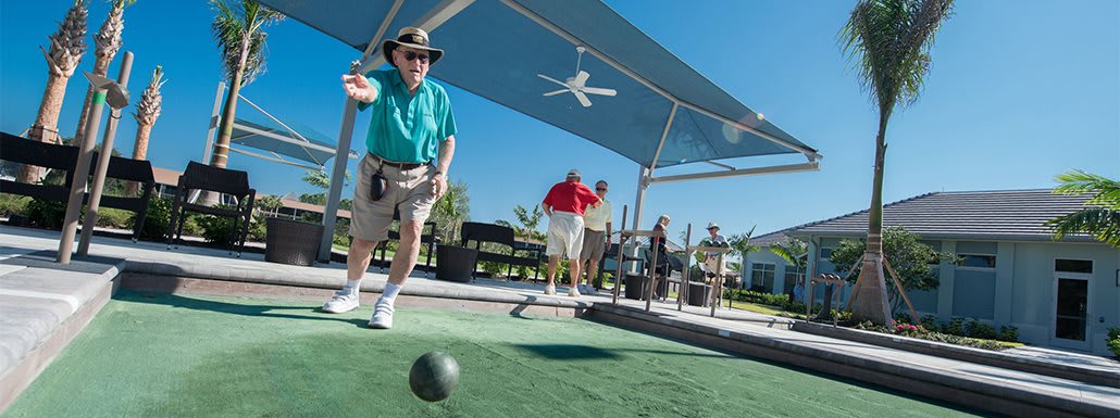 A group of elderly individuals playing bocce ball on a sunny day.