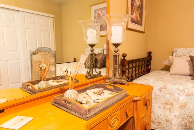 A cozy bedroom featuring a wooden dresser with decorative candles and a mirror.