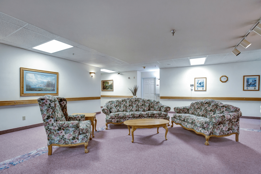 A cozy living room setup with floral-patterned sofas and chairs arranged around a wooden coffee table.