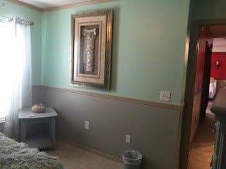 A room interior with a framed painting on the wall, featuring a small table and a trash can.