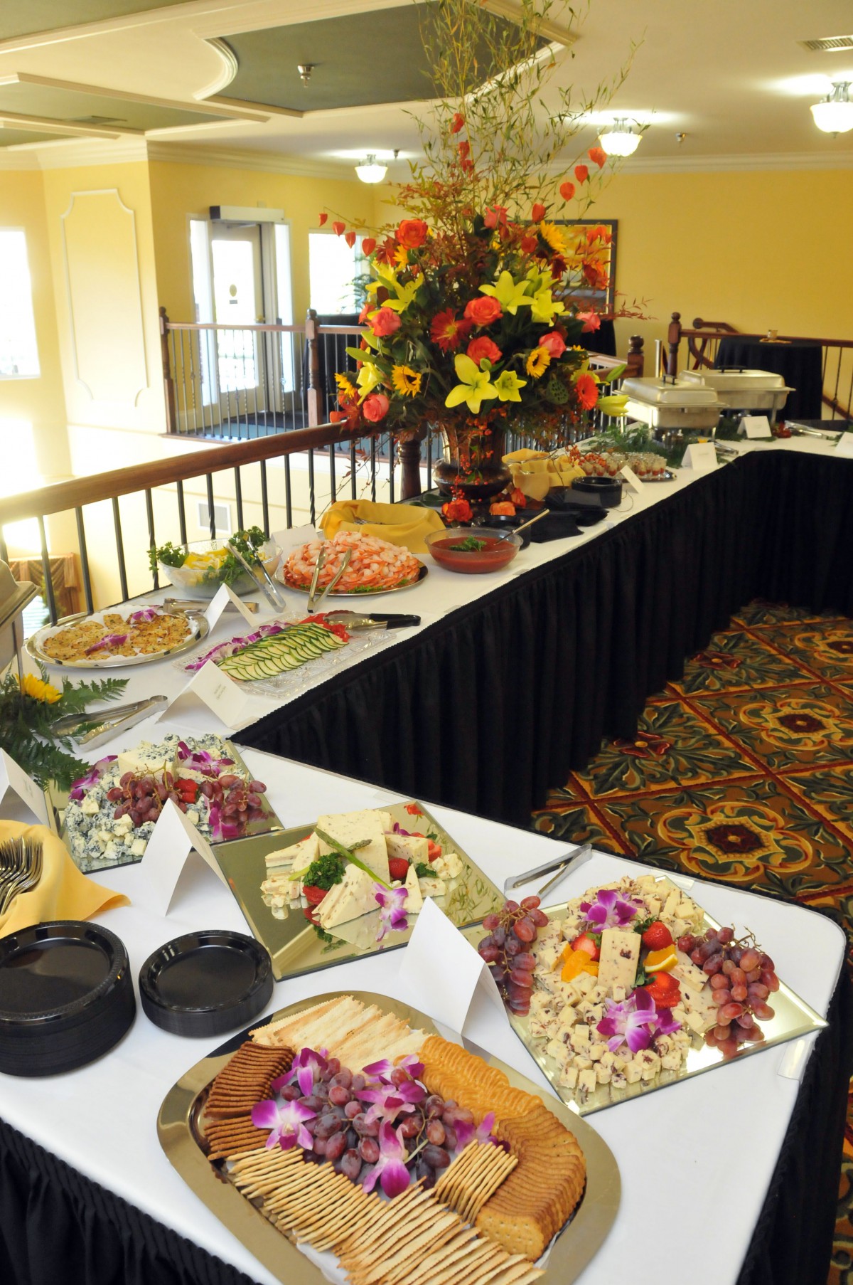 An elegantly arranged buffet table with a variety of dishes and a floral centerpiece, set up for an event.
