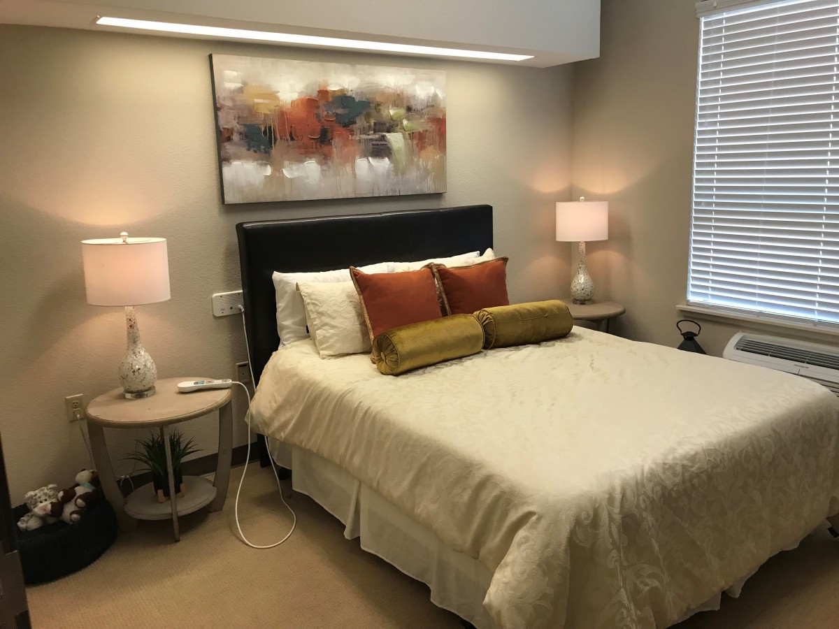 A modern and cozy bedroom with decorative pillows and ambient lighting.