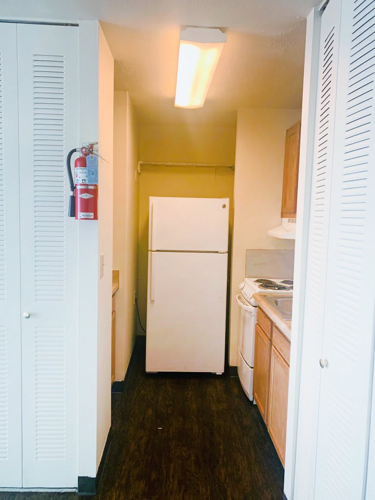 A compact kitchen with essential appliances including a refrigerator, stove, and cabinets.