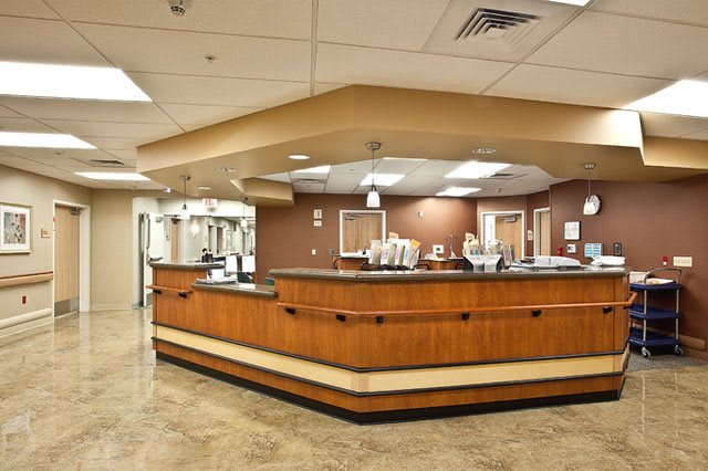 A hospital reception area with a central desk and bright lighting.