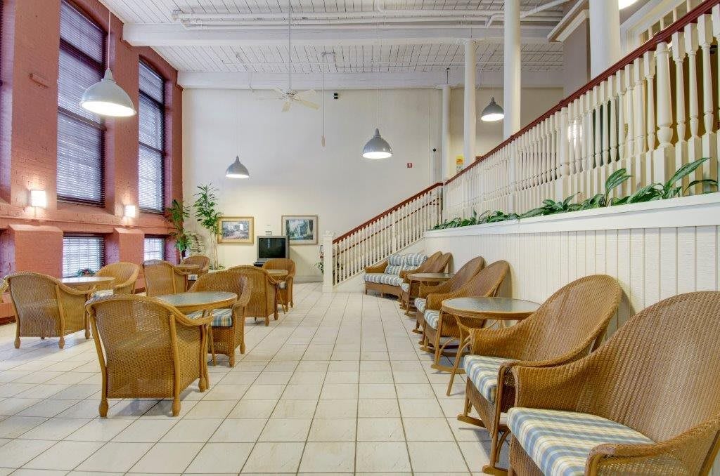 A spacious lobby area with wicker chairs, small tables, and indoor plants.