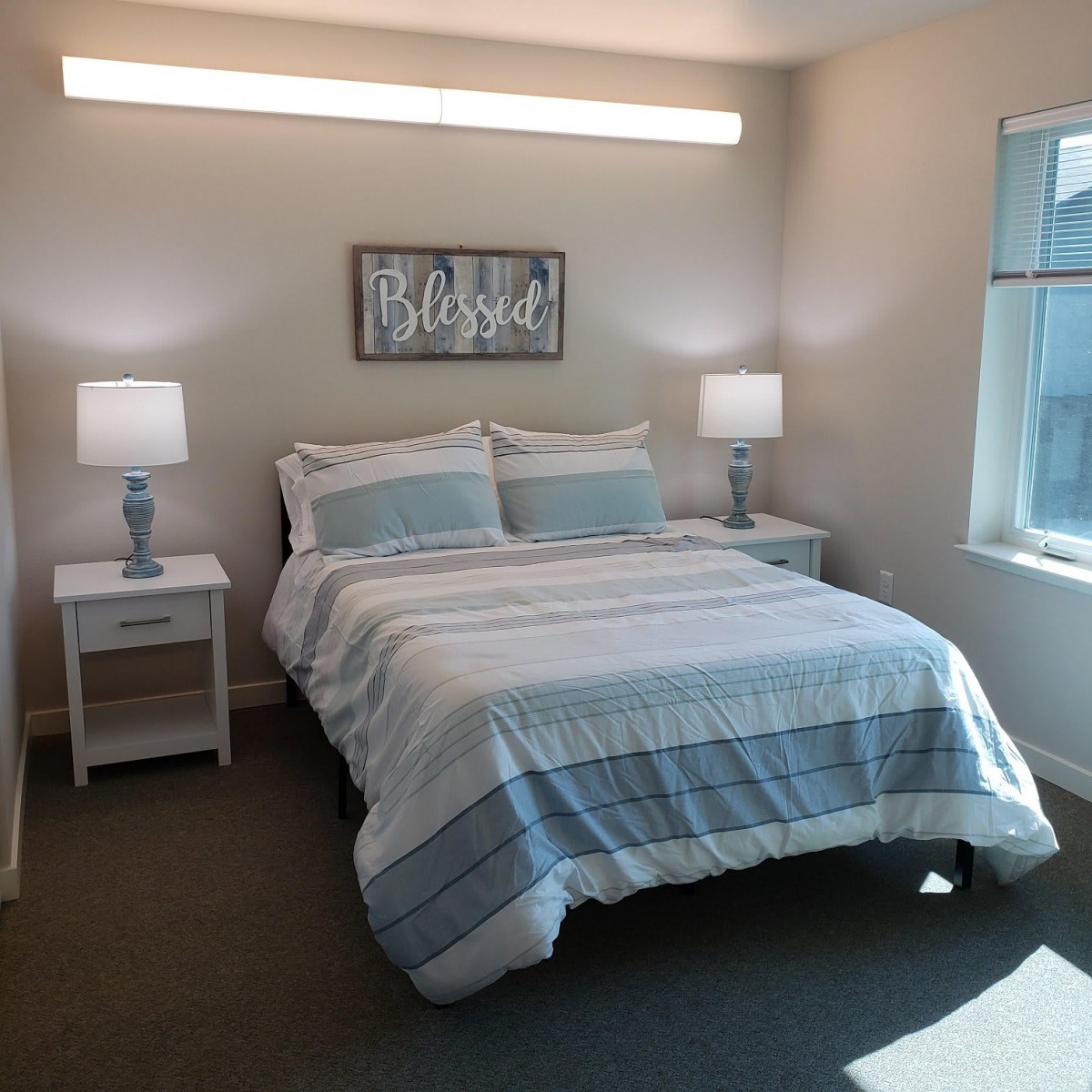 A minimalist bedroom with a neatly made bed and two bedside tables with lamps.