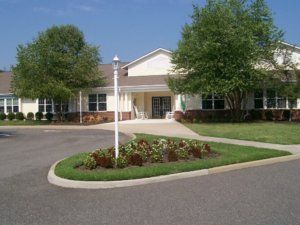 A single-story building with a landscaped circular driveway and trees.