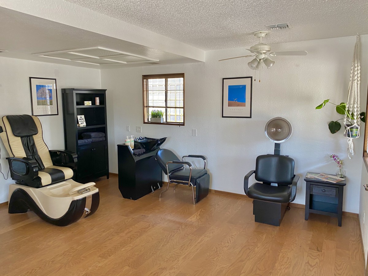 A cozy salon interior with chairs, a hair dryer, and wooden flooring.