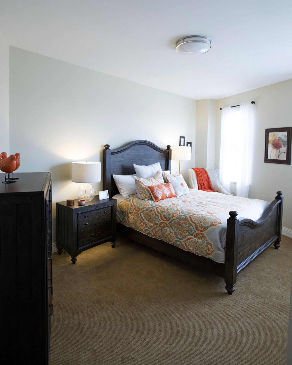 A cozy bedroom with a dark wooden bed, soft bedding, and warm lighting.
