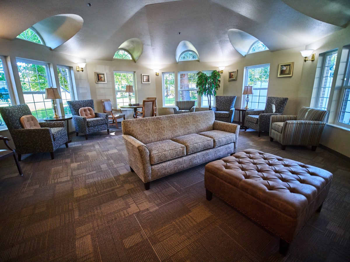 A spacious and well-furnished living room with sofas, armchairs, and large windows allowing natural light.