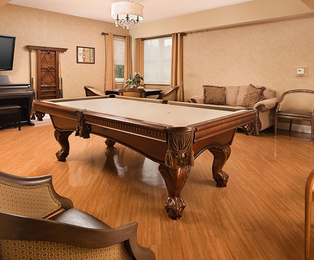 A well-furnished game room featuring a billiard table, comfortable seating, and elegant decor.