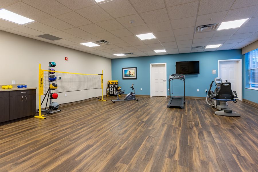 A spacious fitness room featuring a treadmill, medicine balls, and wooden flooring.