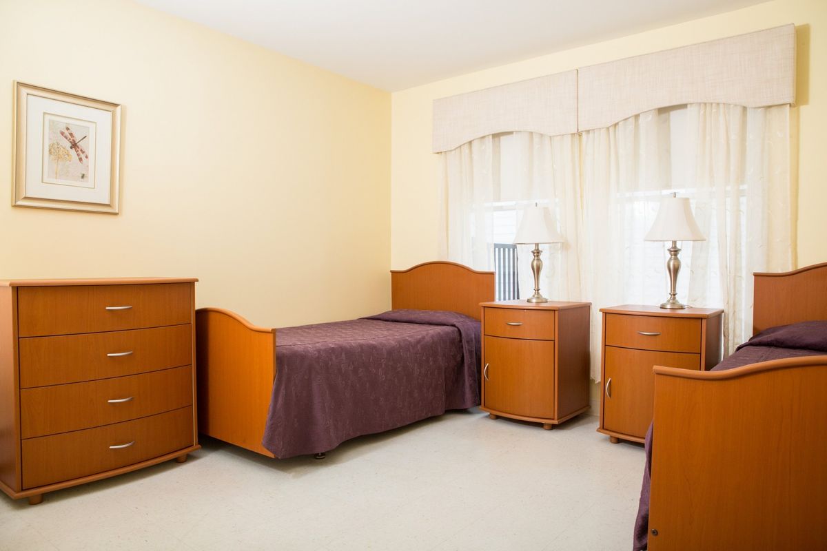 A simple bedroom with a single bed, dresser, and nightstands.