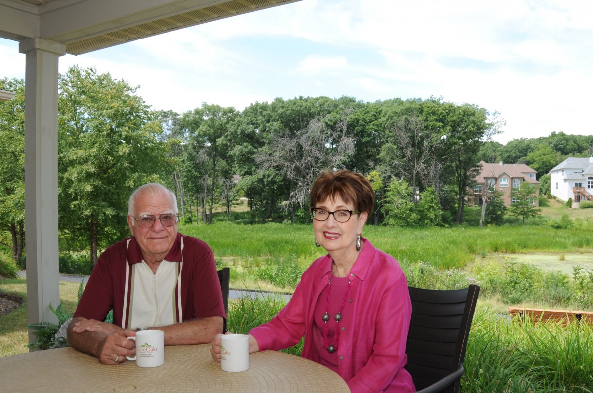 A senior couple enjoying coffee on a patio with a scenic view.