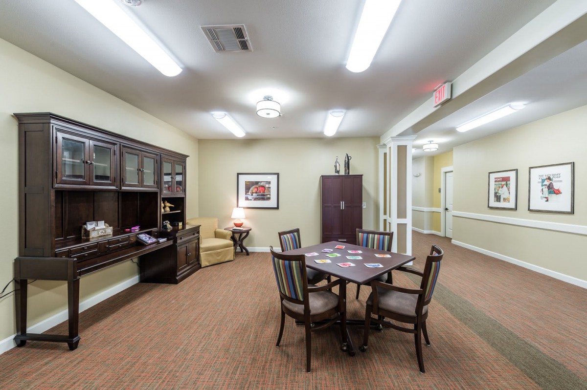 A well-lit office space with a table and chairs, bookshelf, and decorative elements.