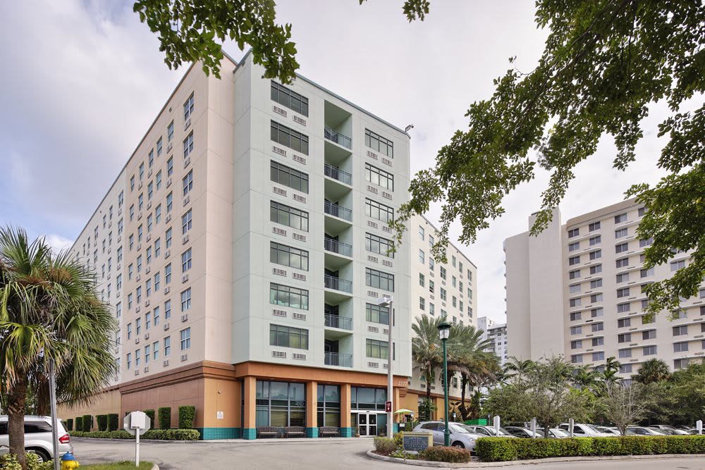 A modern apartment building in an urban setting with cars parked nearby.