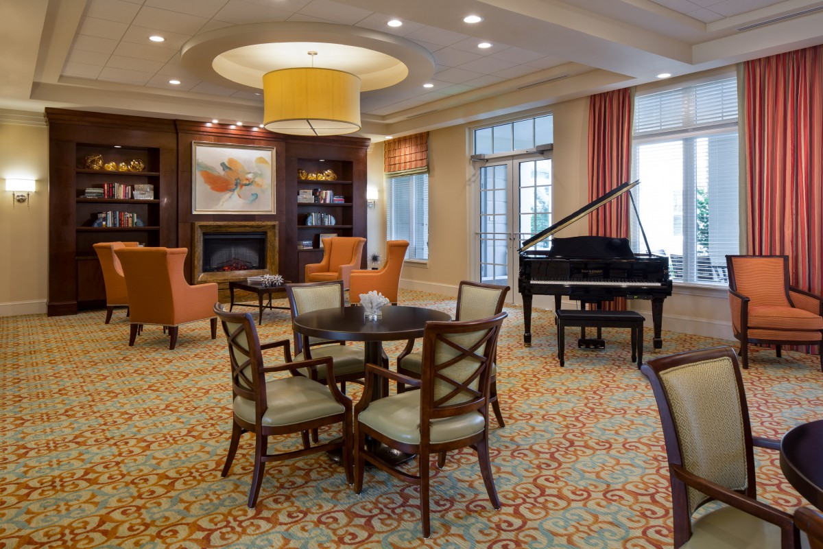 A cozy lounge with a grand piano, seating area, and fireplace.