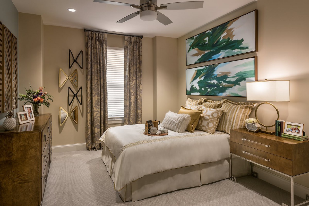 A modern bedroom featuring elegant decor with a comfortable bed, artistic wall hangings, and a ceiling fan.