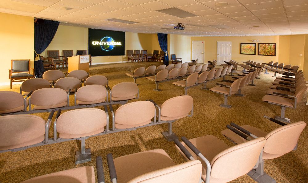 An empty conference room with rows of seats facing a screen ready for a presentation.