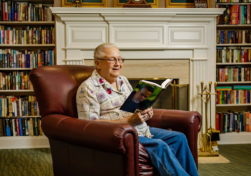 An elderly man enjoys a quiet moment reading in a cozy library setting.