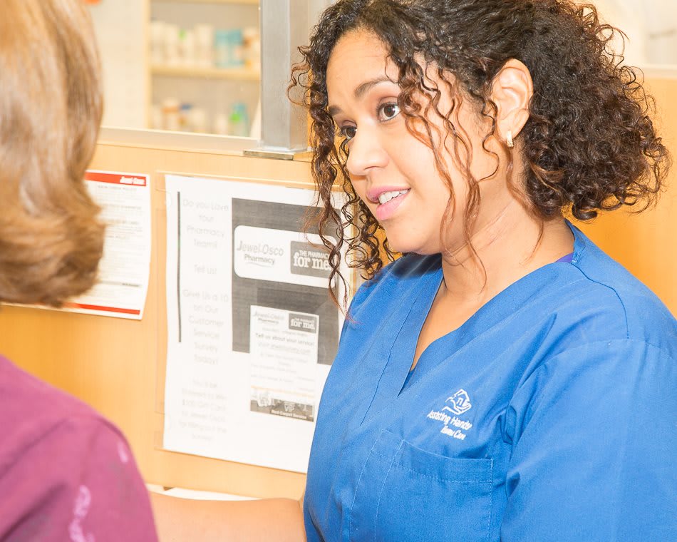 A nurse in blue scrubs talking to a patient, providing healthcare consultation.