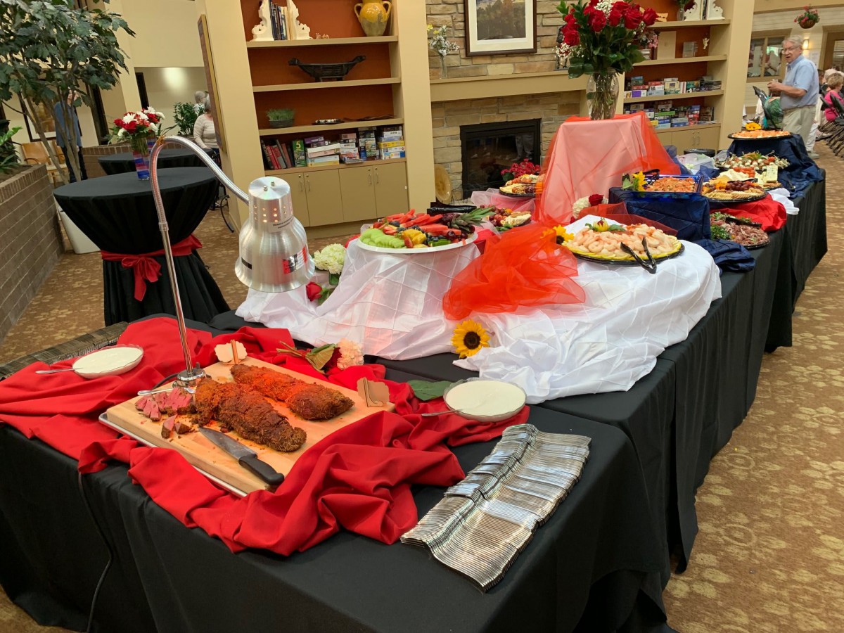 A beautifully arranged buffet table with various dishes, decorated with colorful fabrics and accents, set up for an indoor event.