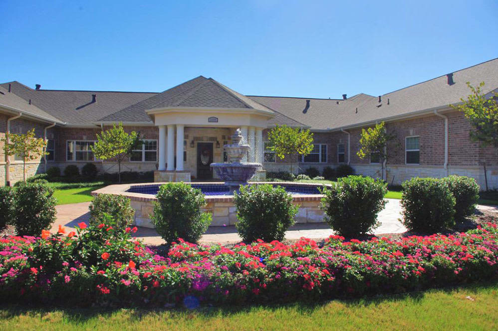 A well-maintained building front with a garden and fountain.