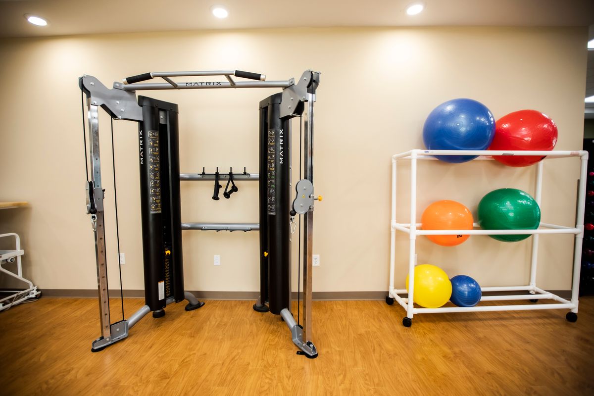 A clean and organized gym space featuring a cable machine and medicine balls.