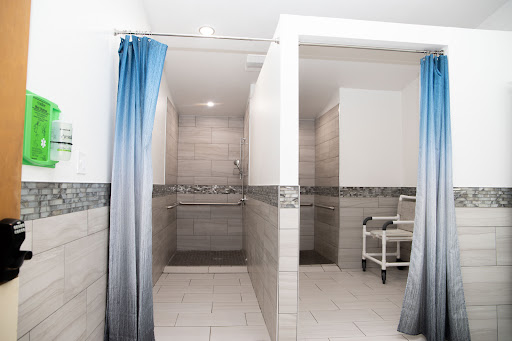 A modern bathroom featuring individual shower stalls with curtains, tiled walls, and a clean aesthetic.