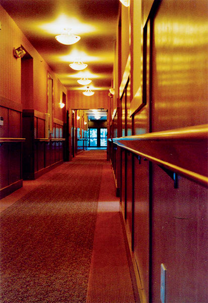 A dimly lit hallway with carpet flooring and wooden panels.