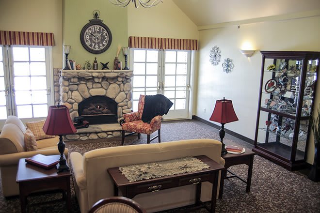 A cozy living room with a stone fireplace, sofa, chairs, and decorative elements.