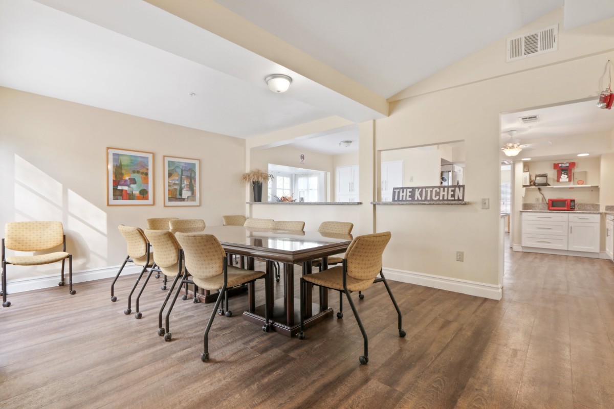 A modern dining room with a wooden table, beige chairs, and artwork on the walls.