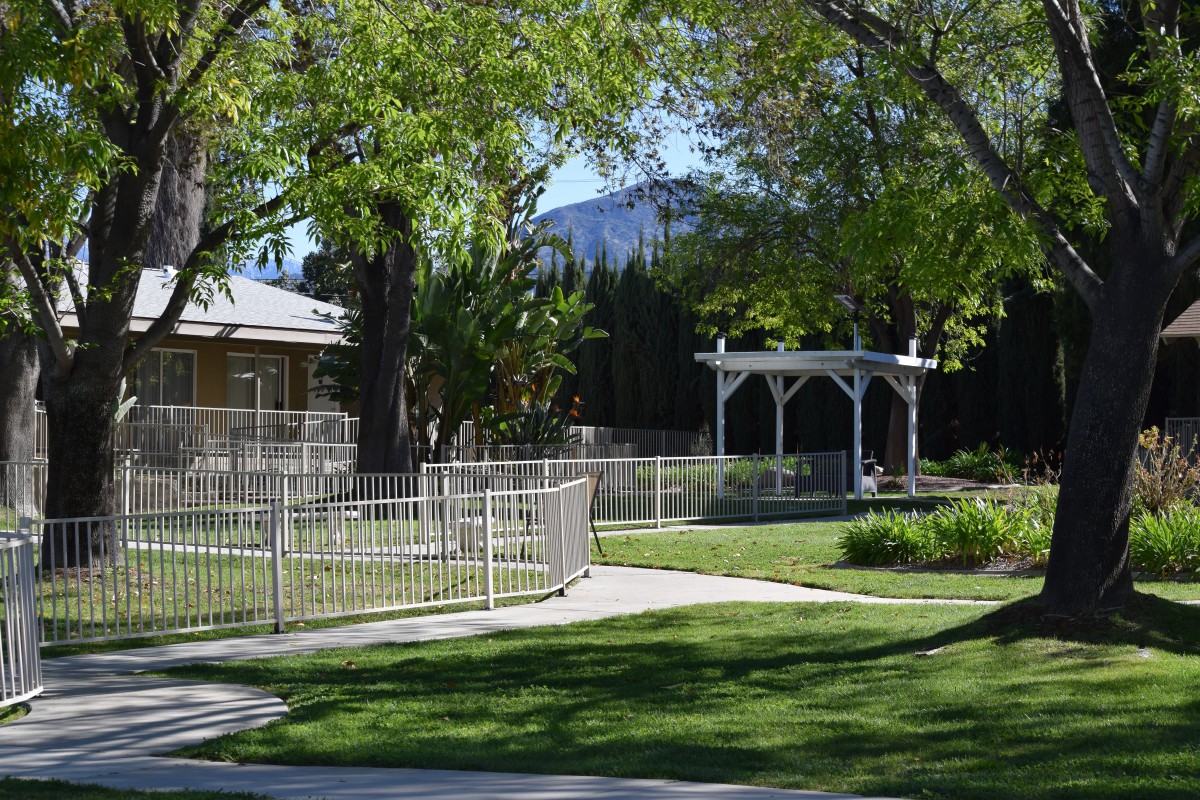 A serene garden with a white gazebo, surrounded by trees and a well-maintained lawn.