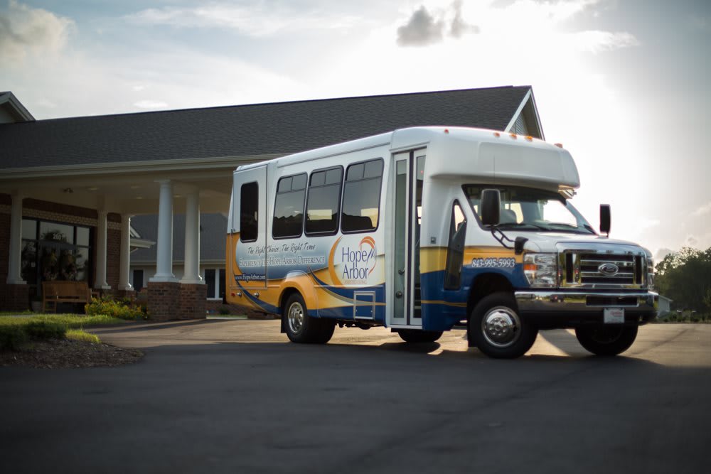 A shuttle bus parked in front of a building on a sunny day.