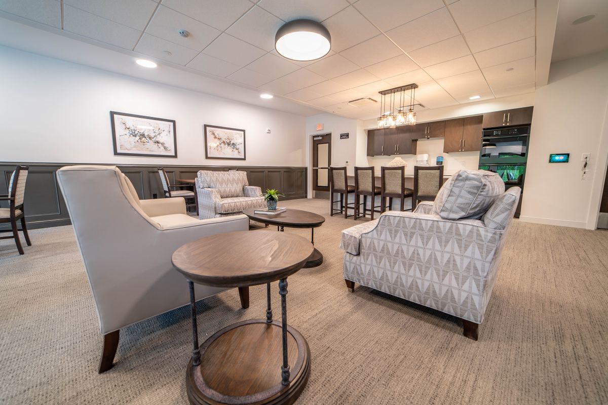A modern living room with comfortable seating, featuring a spacious open layout connected to the kitchen.