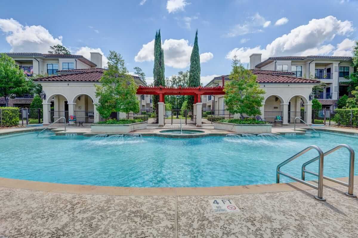 A beautifully designed outdoor pool area with surrounding architecture and trees.