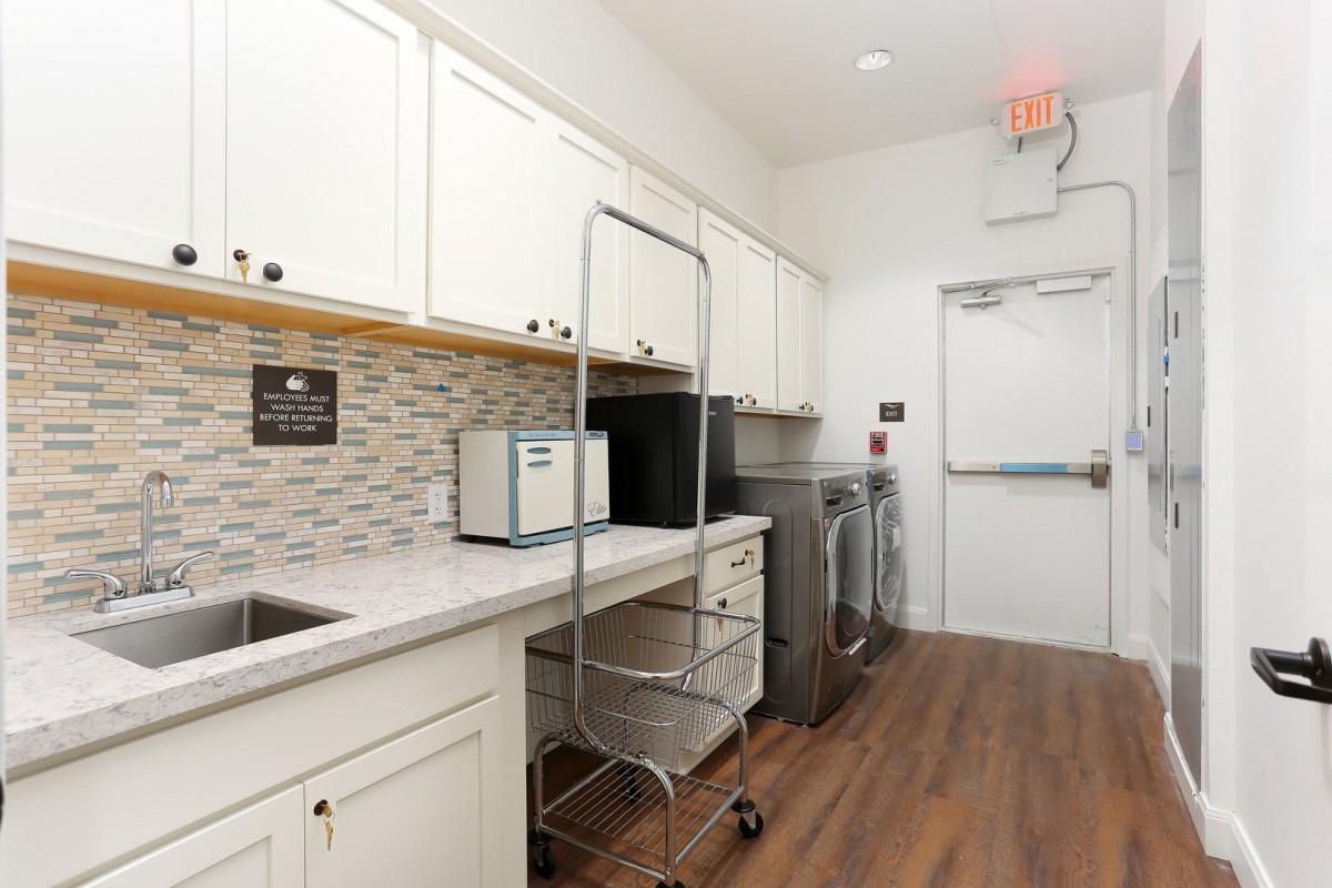 A modern laundry room with white cabinets, a washer and dryer, and wooden flooring.