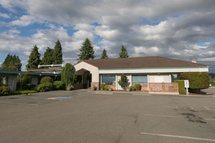 A standalone building with a parking lot under a cloudy sky.