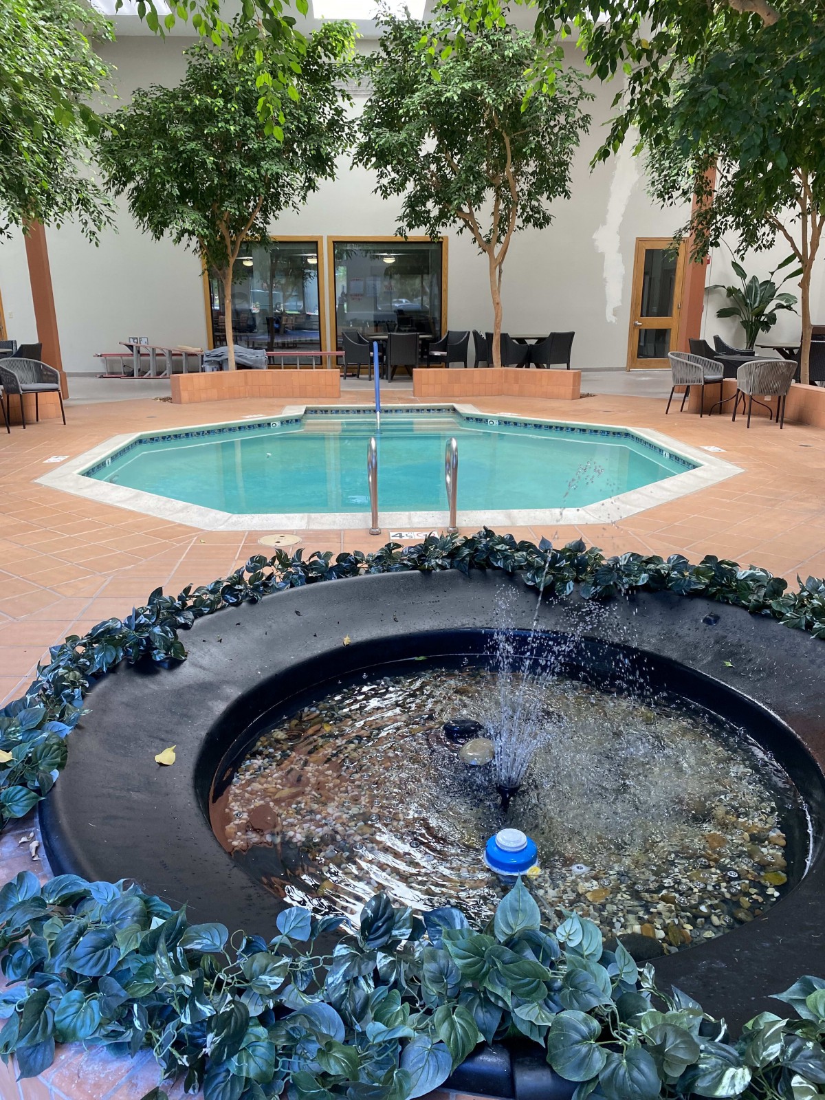 Indoor pool and fountain area with surrounding plants and seating.