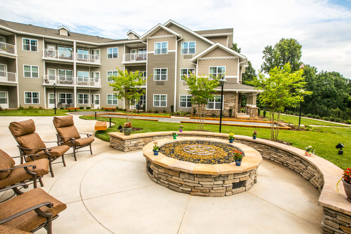 A modern apartment complex featuring a landscaped courtyard with a fire pit and outdoor seating.